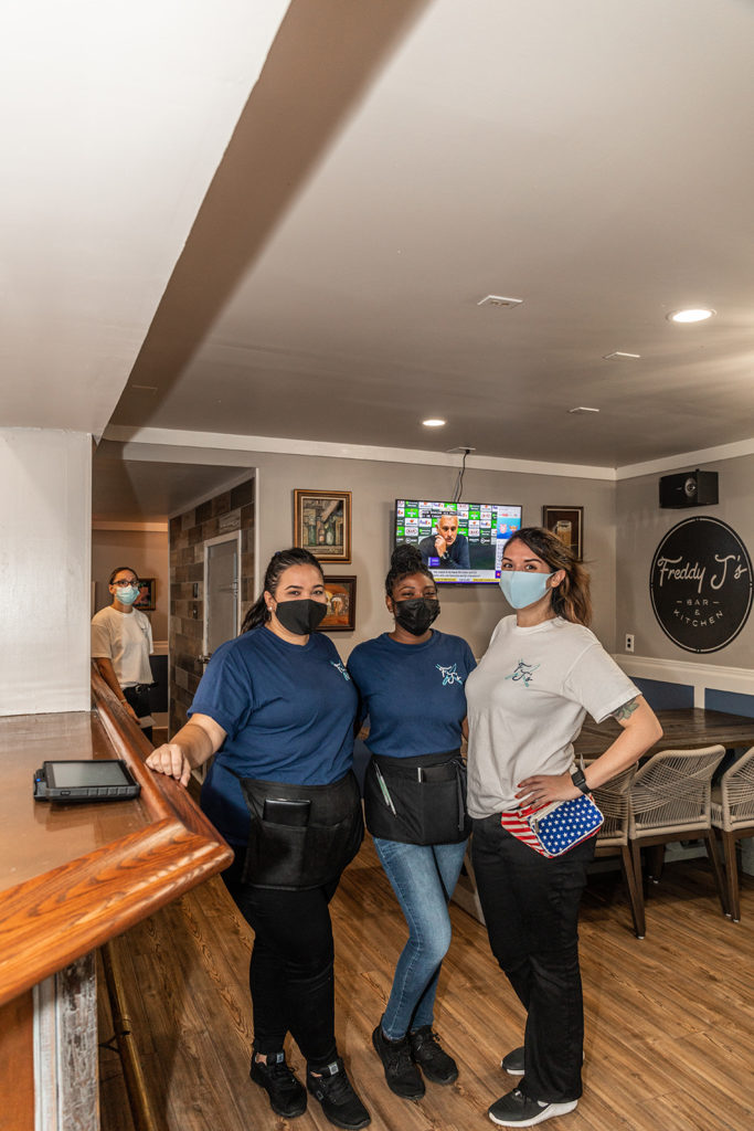 Three staff members smiling under their masks in Freddy J's Bar & Kitchen in Mays Landing, NJ