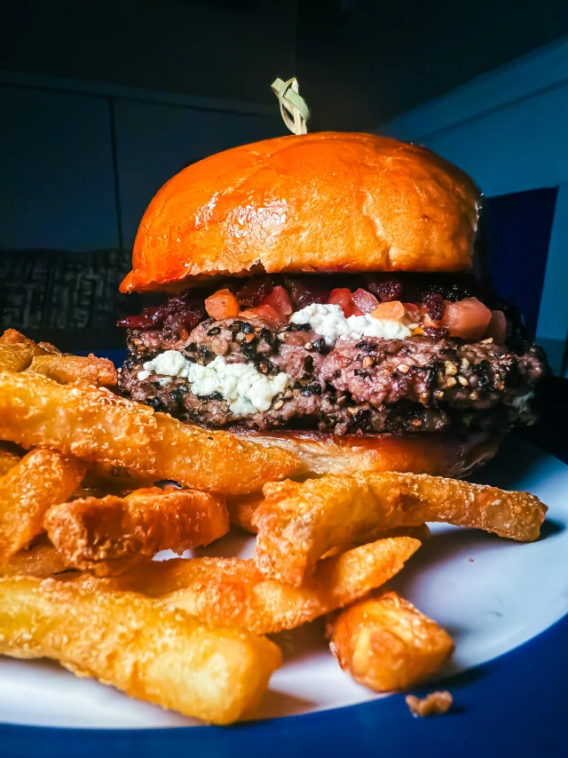 Two smashed patties, crusted with black pepper and dripping with flavor.

We stack them with crumbled blue cheese, house-smoked tomatoes, and a thick swipe of bacon jam to hit every salty, smoky, tangy craving at once.

It comes with fries, but let’s be honest, you’ll be locked in on the burger.